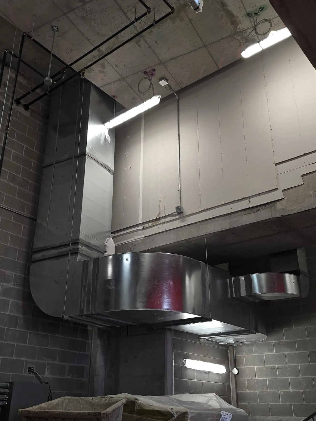 Galvanized rectangular ductwork with a large radius offset in a block-walled plant room
